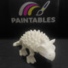 A front perspective view of a white 3D printed Ankylosaurus skeleton. The image highlights the dinosaur's skull, horns, and the rows of textured spikes leading down its articulated back.