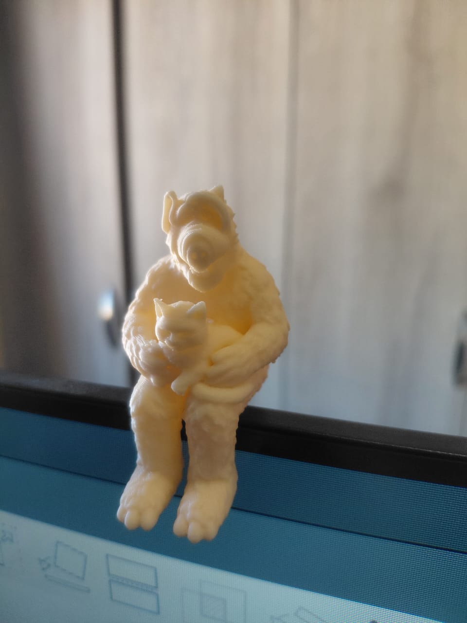 Alf figure holding a cat, sitting on a monitor.