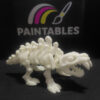 A side profile view of a white articulated 3D printed Sabertooth Tiger skeleton. The model is standing on a black surface, highlighting its curved spine, segmented ribs, and prominent saber-shaped fangs.